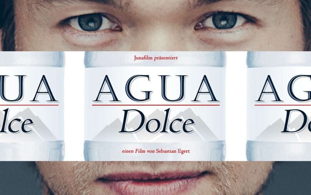The face of a man being covered by the title "Junafilm präsentiert Agua Dolce - Einen Film von Sebastian Egert."