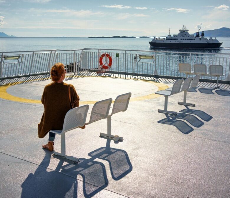 A woman sitting on a boot's deck looking on the ocean