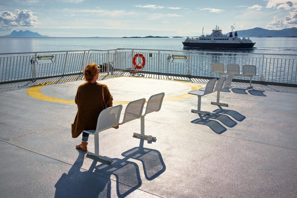 A woman sitting on a boot's deck looking on the ocean